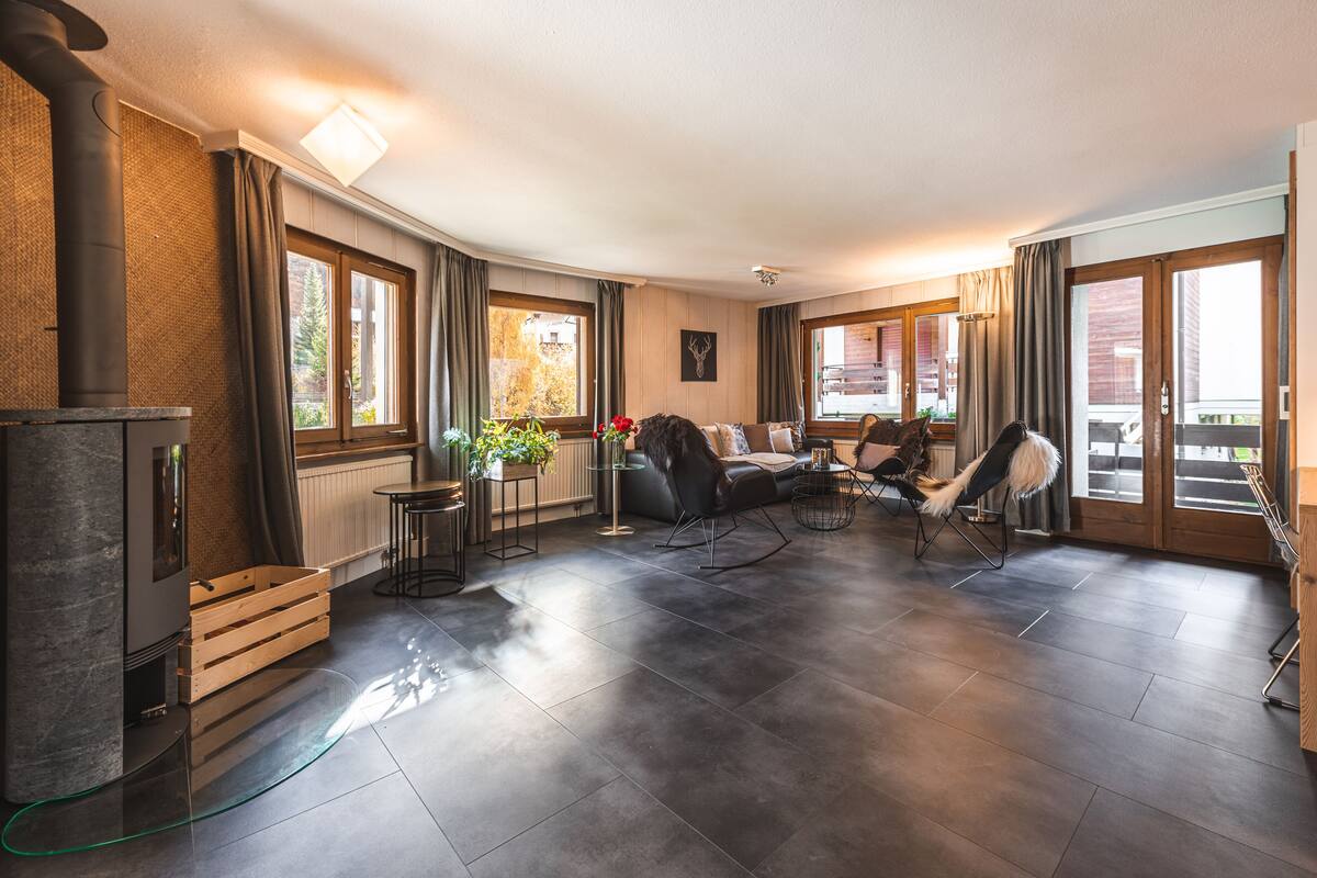 A spacious living room with a stone fireplace, large windows, and a cozy seating area.