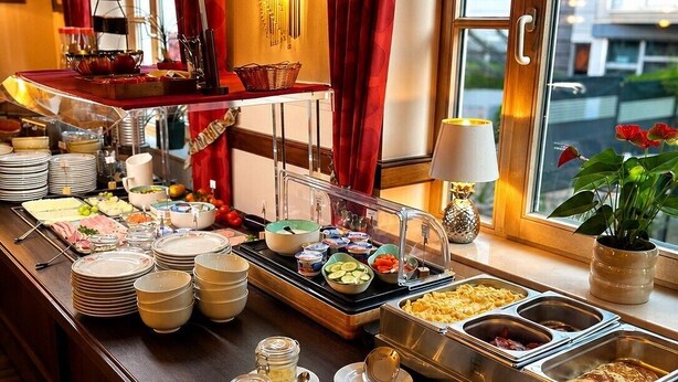Een buffetopstelling met diverse gerechten, borden en bestek.