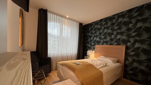 Een hotelkamer met een bed, een stoel, een bureau en een muur met een geometrisch patroon.