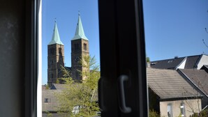 Uitzicht op twee kerktorens door een raam, met een heldere lucht op de achtergrond.