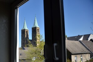 Uitzicht op twee kerktorens door een raam, met een heldere lucht op de achtergrond.