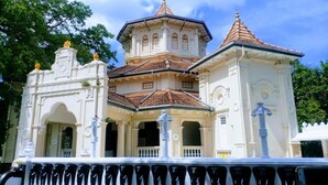 A white building with a central tower and two smaller towers, featuring ornate architectural details and a tiled roof. - Sai Sea City Hotel (Colombo)