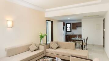 A modern living room with two sofas, a coffee table with snacks, and a dining area with a table and chairs.
