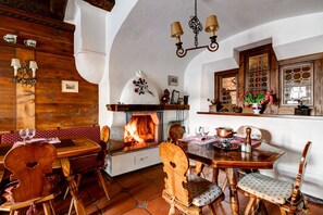 A rustic dining room with a fireplace, wooden furniture, and a tiled floor. - Hotel Parsenn (Davos)