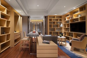 Ein modernes Wohnzimmer mit eingebauten Holzregalen, einem Essbereich mit Tisch und Stühlen und einer gemütlichen Sitzecke mit Sofa und Sesseln.