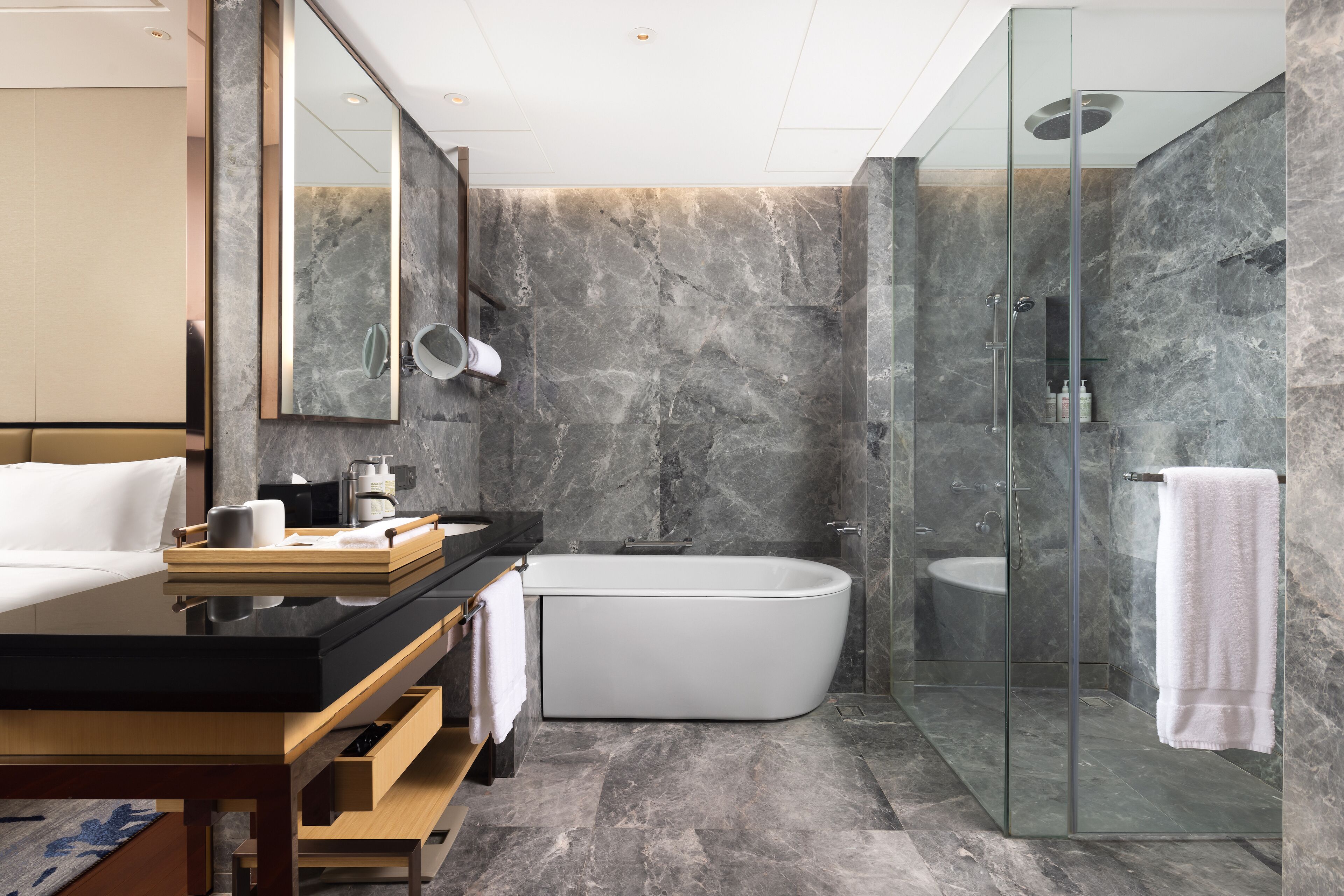 Un baño moderno con ducha de vidrio, bañera independiente y tocador con espejo y perchero para toallas.