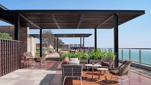 Une terrasse sur le toit avec des sièges extérieurs, une vue sur la mer et un espace couvert agrémenté d’une pergola.