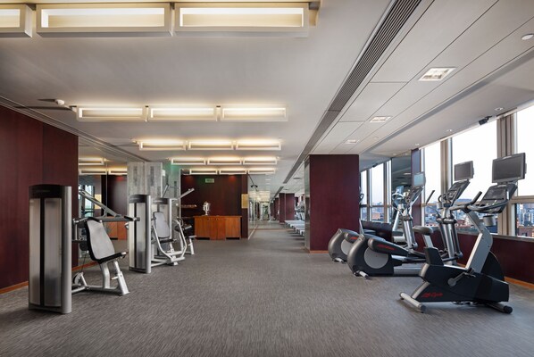 Une salle de sport équipée de machines de cardio, de postes d’entraînement avec poids et d’un espace d’accueil.