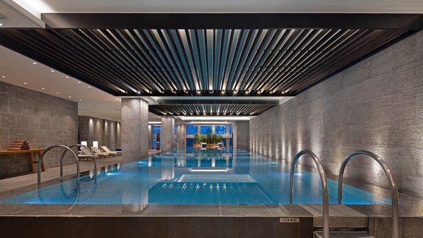 Une piscine intérieure moderne offrant une vue dégagée sur le paysage urbain grâce à de grandes fenêtres.