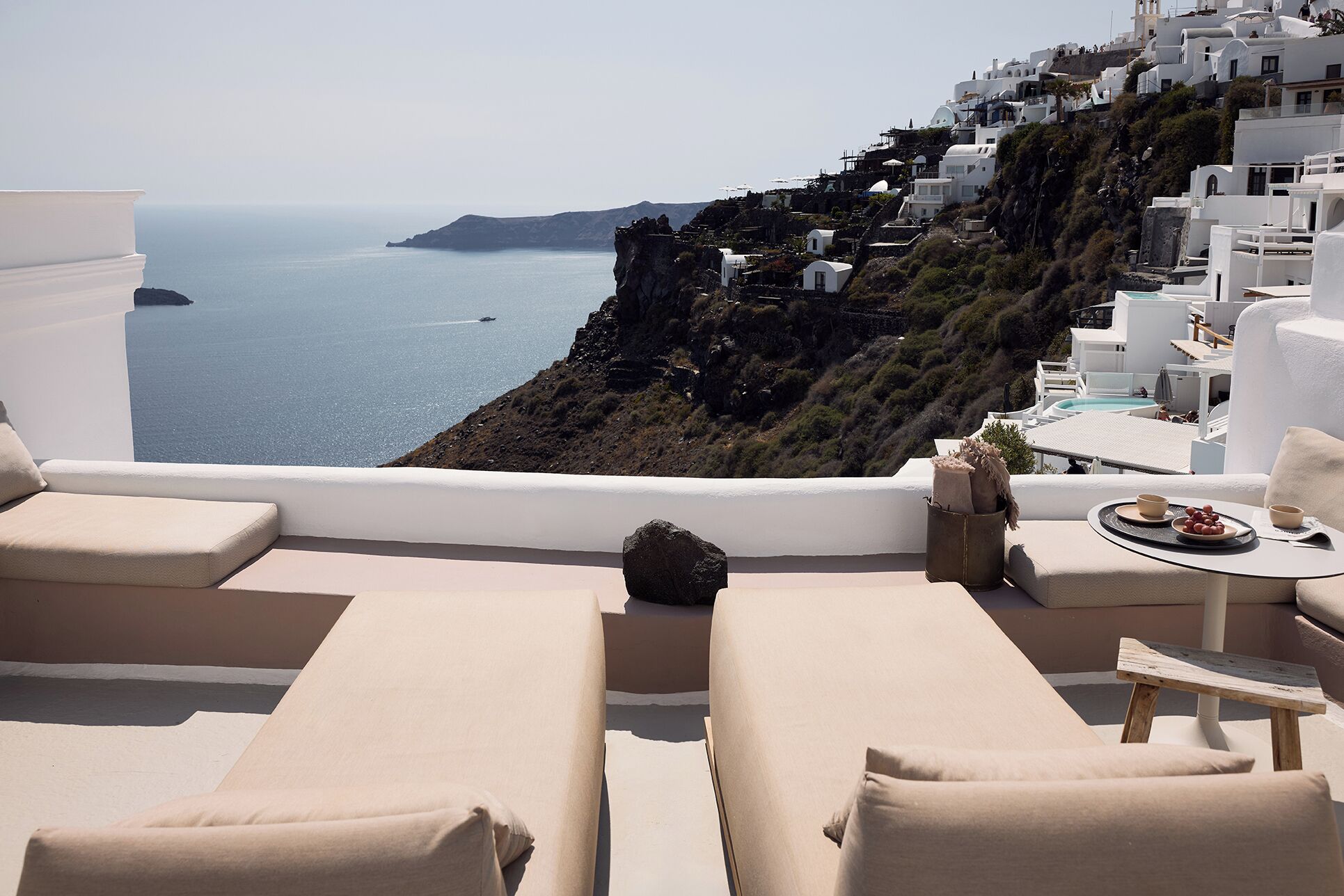 A terrace with white furniture overlooking a coastal view.