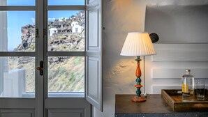 A room with a view of rocky terrain and white buildings outside a window. - Iconic Santorini by Sandglass (Santorini)