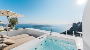 A rooftop infinity pool with a view of the sea, a lounge area with cushions, and a bottle of wine. - Iconic Santorini by Sandglass (Santorini)