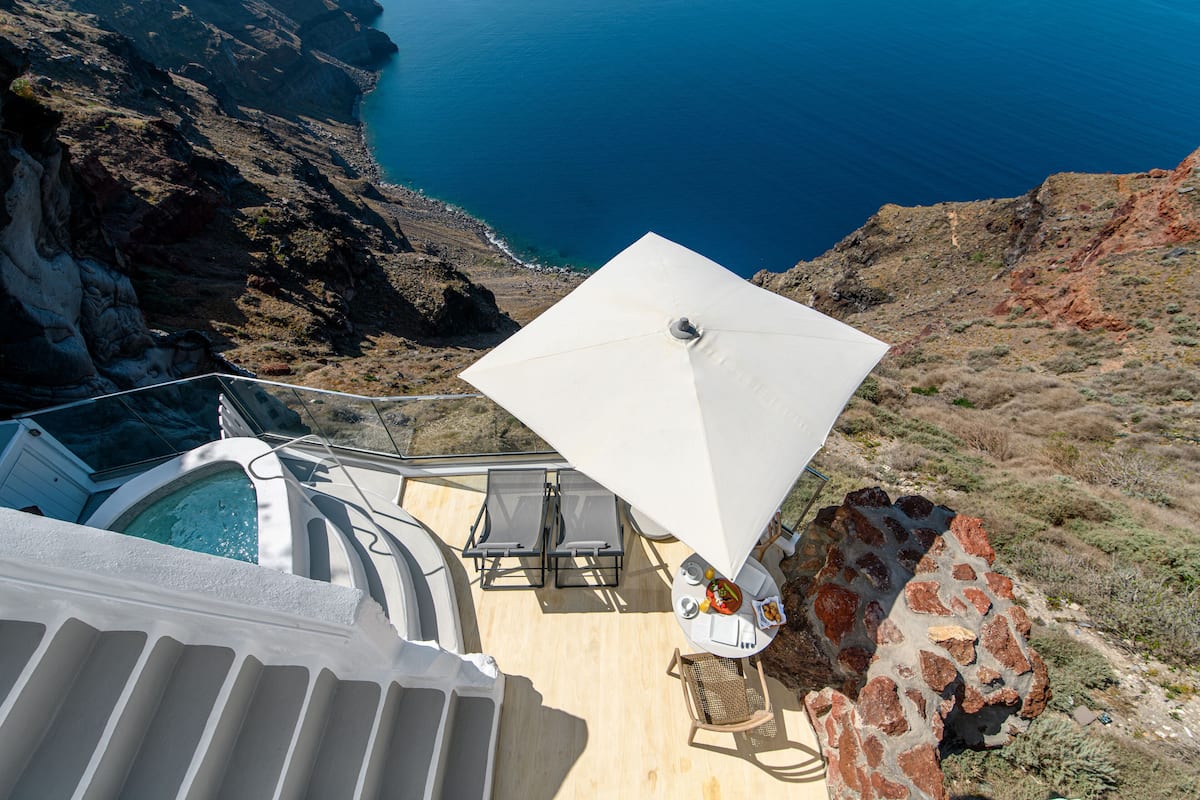 A rooftop terrace with a hot tub, lounge chairs, and a table with food.