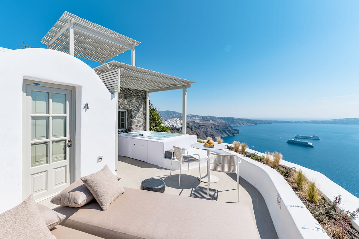 A white building with a patio, outdoor seating, and a view of the sea.