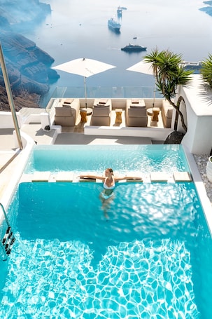 Una piscina techada, sombrillas, sillones reclinables de piscina