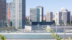 Une vue urbaine avec des immeubles modernes de grande hauteur, une piscine et quelques espaces verts au premier plan.
