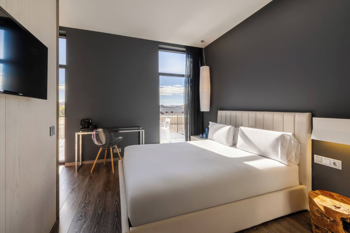 Une chambre d’hôtel moderne dotée d’un grand lit, d’un bureau, d’une télévision à écran plat et offrant une vue sur l’extérieur.