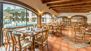 Un restaurant avec des tables et des chaises en bois, de grandes fenêtres et un sol carrelé.