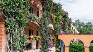 Un bâtiment doté de fenêtres en arc de cercle et de balcons, recouvert de verdure et de fleurs.