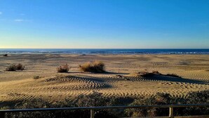 A sandy beach with a wooden fence in the foreground and a clear blue sky. - Residence Côté Mer (La Grande-Motte)