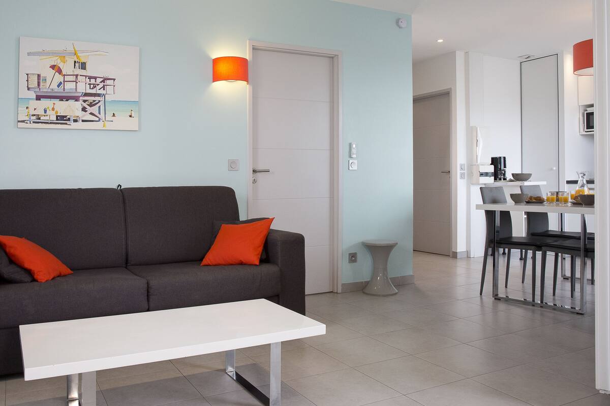Ein modernes Wohnzimmer mit einem grauen Sofa, einem weißen Couchtisch und einem Gemälde an der Wand.