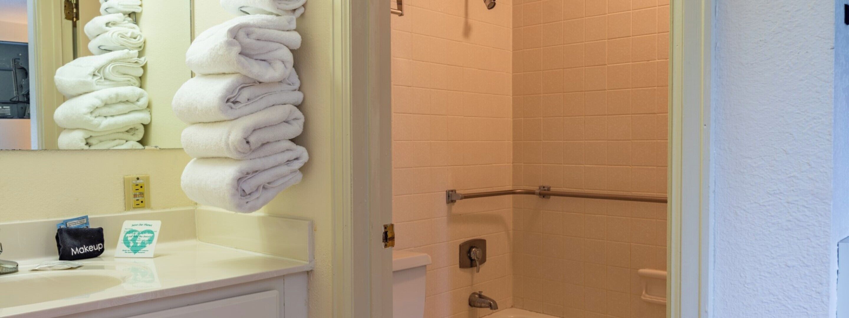 A bathroom with a sink, mirror, and stacked towels.