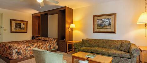 A hotel room with two beds, a sofa, a small table, and a lamp.