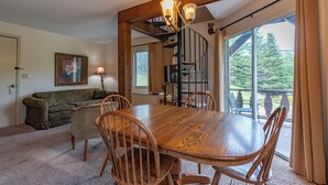 A dining area with a wooden table and chairs, a chandelier, and a view of a balcony with a railing. - 4 Seasons at Beech Mountain (Banner Elk)