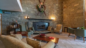 A stone-walled room with a fireplace, patterned sofas, and a coffee table. - 4 Seasons at Beech Mountain (Banner Elk)