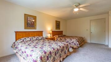 A bedroom with two beds, a ceiling fan, and two wall-mounted lamps.