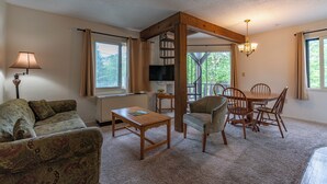 A living room with a sofa, coffee table, TV, and a dining area with chairs and a table. - 4 Seasons at Beech Mountain (Banner Elk)