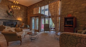 A cozy living room with stone walls, a fireplace, and a television.