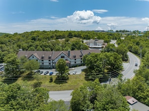 A large, two-story building with a traditional architectural style, surrounded by lush greenery and a winding road.