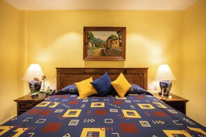 A bed with a patterned bedspread, two bedside lamps, and a painting above the bed. - Lindo Mar Resort (Puerto Vallarta)