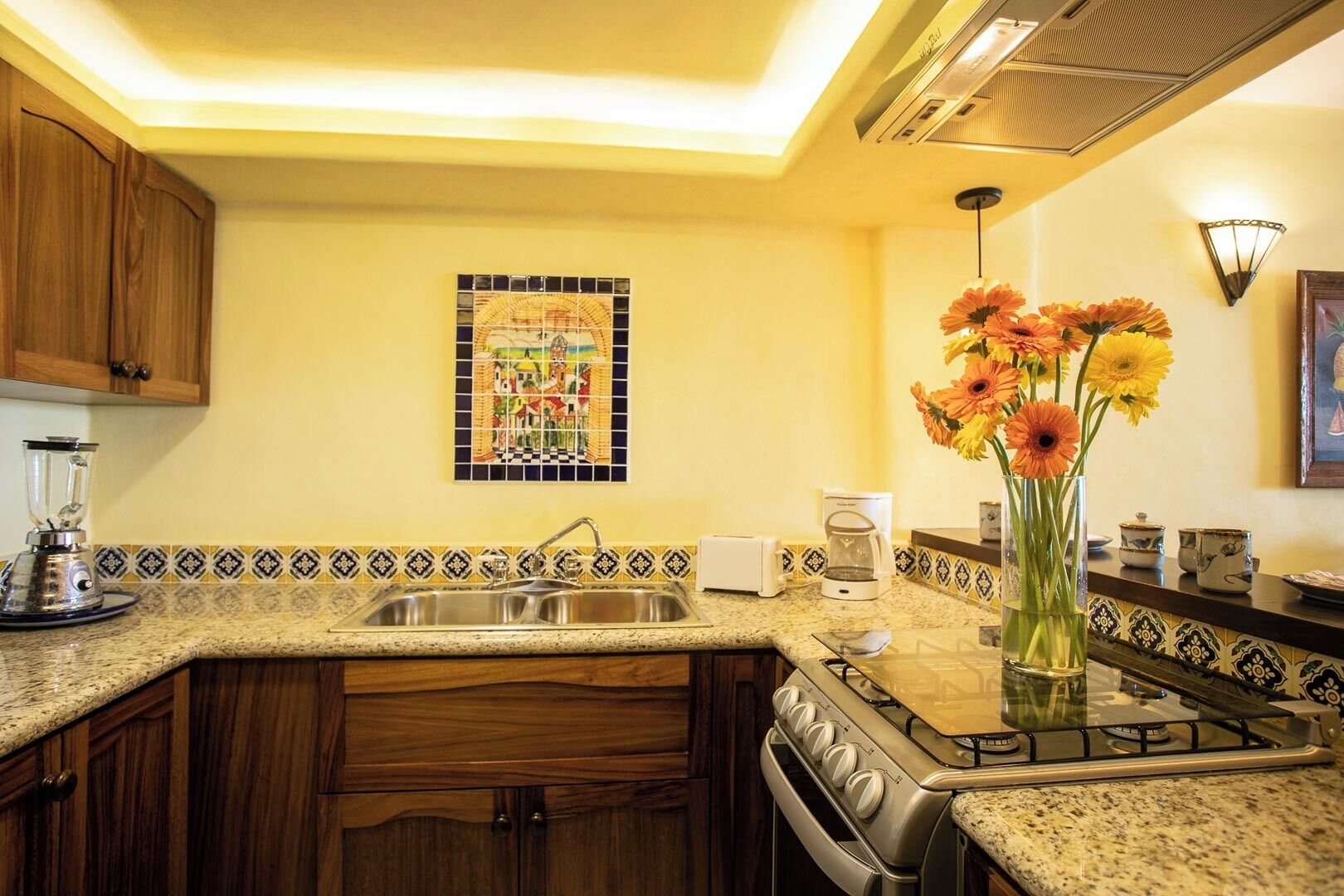 Una cocina con encimera de granito, estufa, lavabo y cafetera.