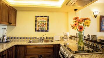 Una cocina con encimera de granito, estufa, lavabo y cafetera.