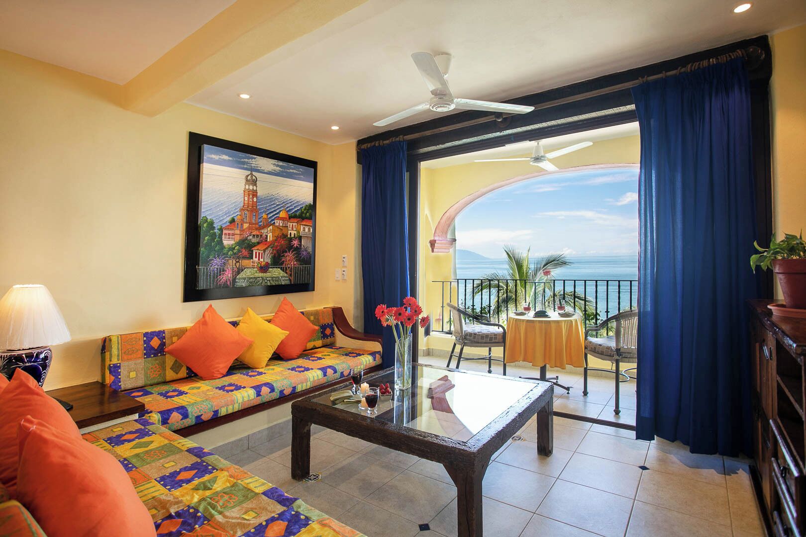 A living room with a sofa, coffee table, and a painting of a lighthouse.