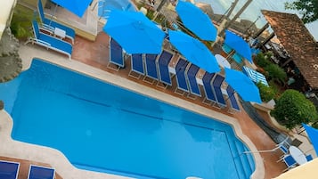 Une piscine avec des parasols bleus et des chaises longues.
