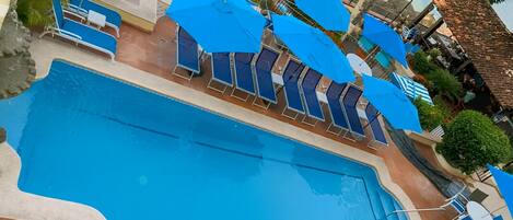 A swimming pool with blue umbrellas and lounge chairs.