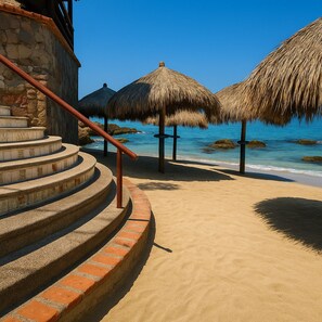 A spiral staircase leading to a beach area with thatched umbrellas and a view of the ocean. - Lindo Mar Resort (Puerto Vallarta)