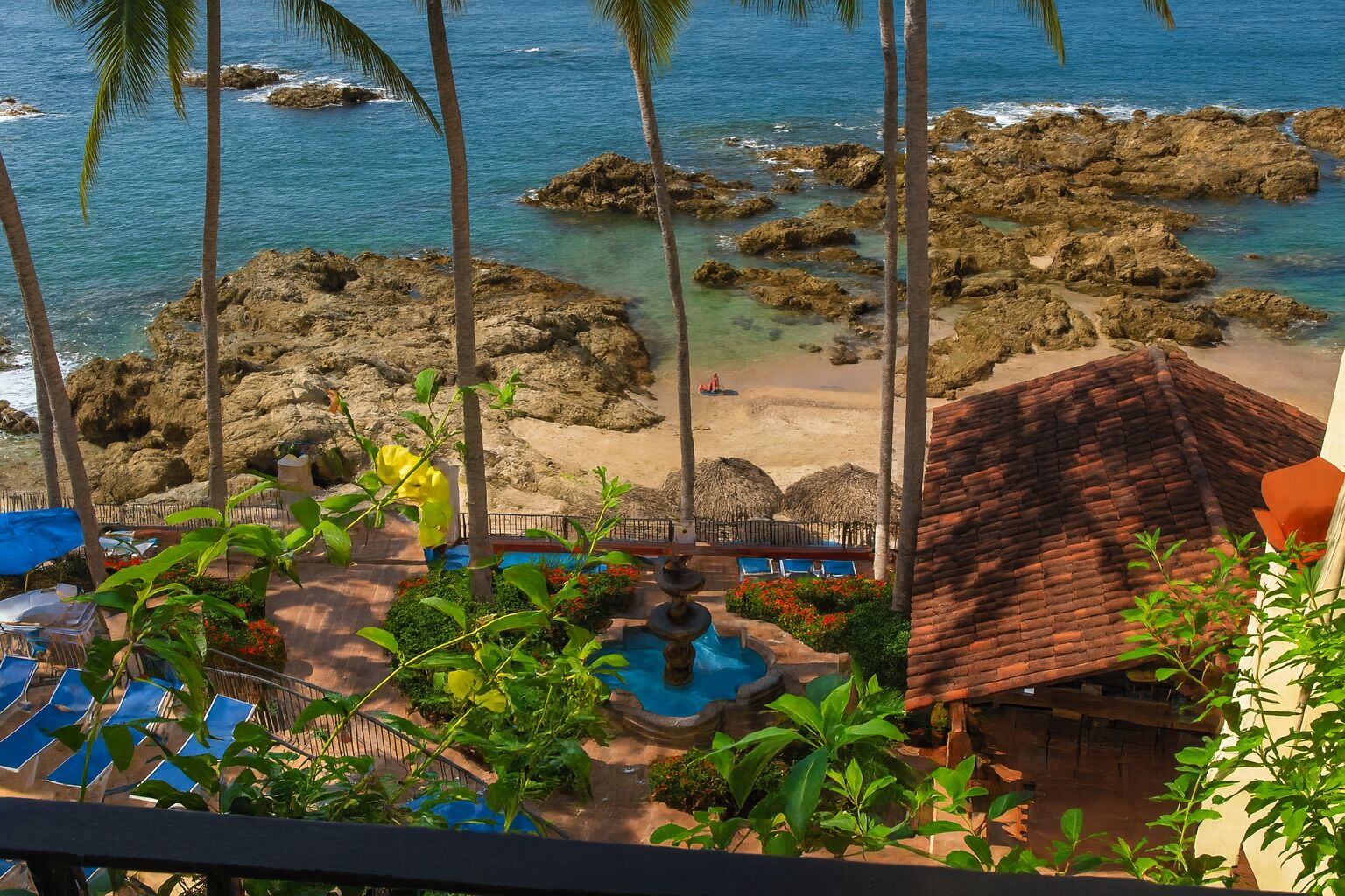 Ein Resort mit Pool, Liegestühlen und Blick auf das Meer und die felsige Küste.