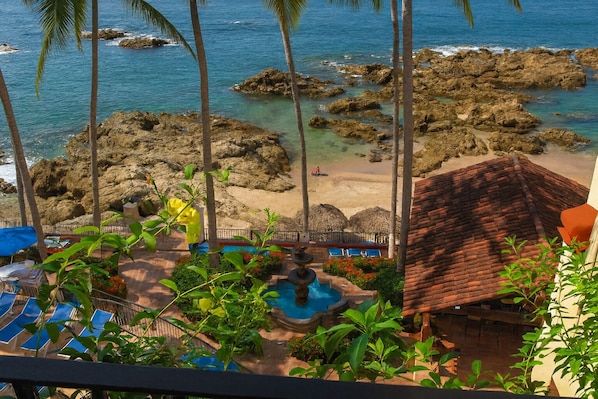 Un resort con piscina, sillas de descanso y vistas al océano y a la costa rocosa.
