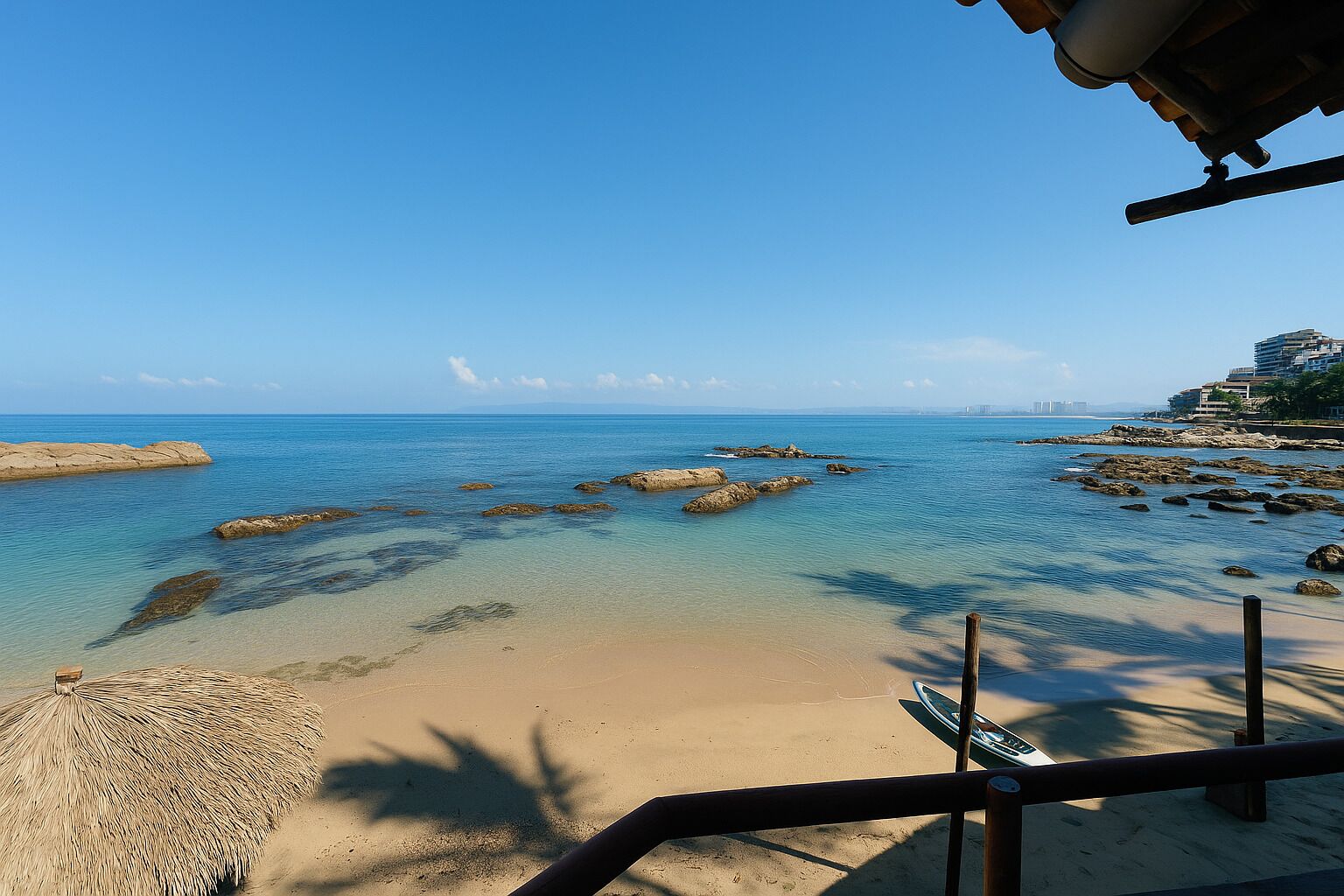 Una playa con agua cristalina, rocas y un horizonte urbano distante.