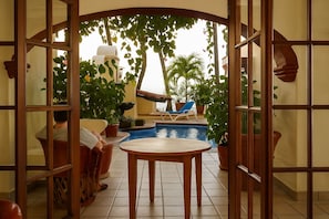 A pool area with a table and chairs, surrounded by potted plants and a view of the sea. - Lindo Mar Resort (Puerto Vallarta)