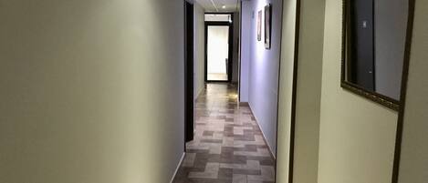 A hallway with a herringbone tile floor, light-colored walls, and a door at the end.