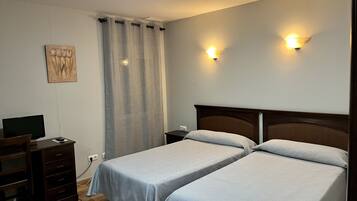 Hotelkamer met twee bedden, een bureau, een stoel, een televisie en twee wandlampen.
