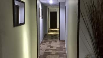Un pasillo con piso estampado, un espejo enmarcado y una puerta al final.