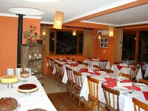 Un restaurante con varias mesas dispuestas para comer, con manteles blancos y sillas de madera.