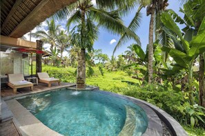 A pool area with lounge chairs, a statue, and lush tropical vegetation. - Puri Gangga Resort Ubud (Sebatu)
