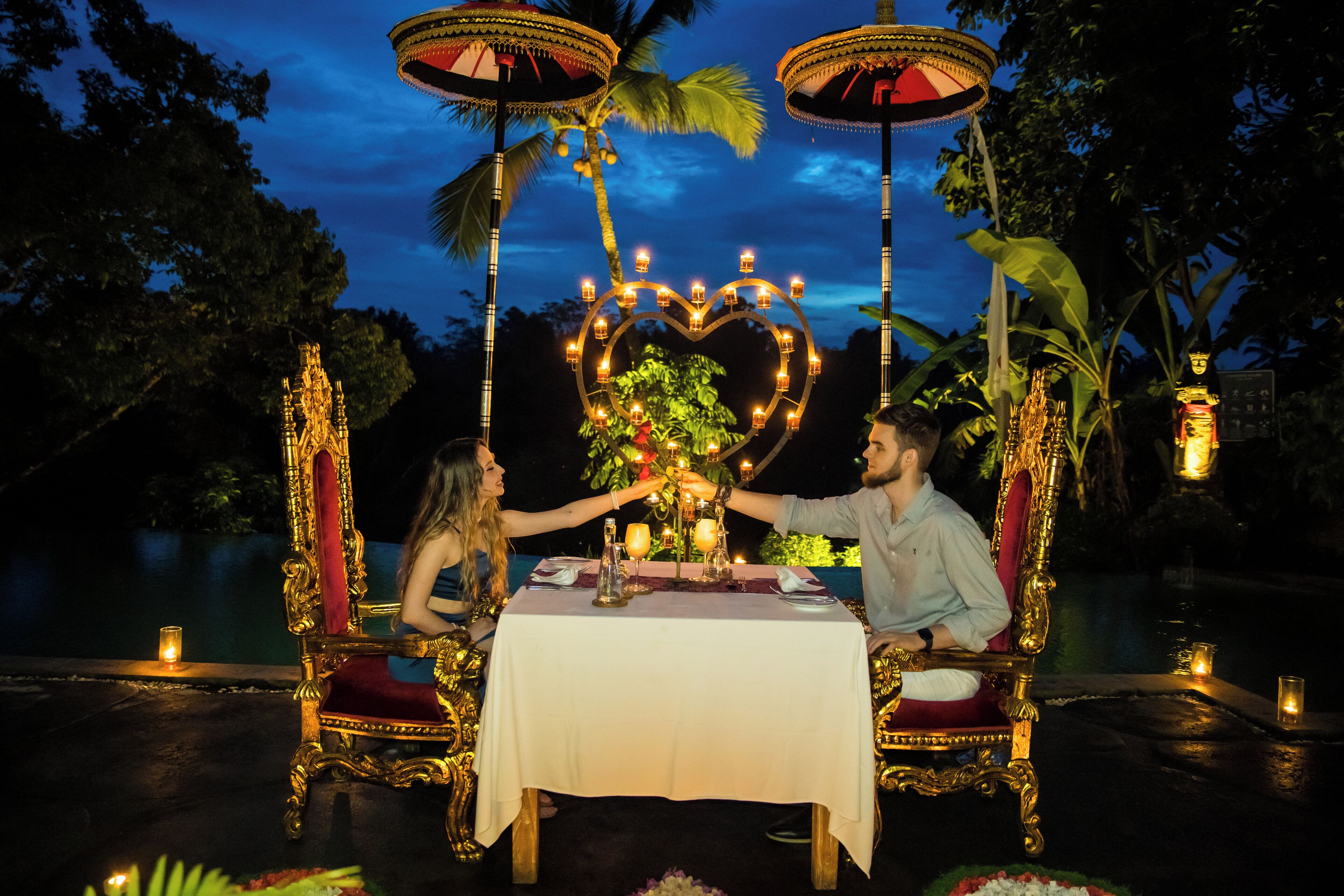 A romantic outdoor dining setup with ornate chairs and a heart-shaped light decoration.